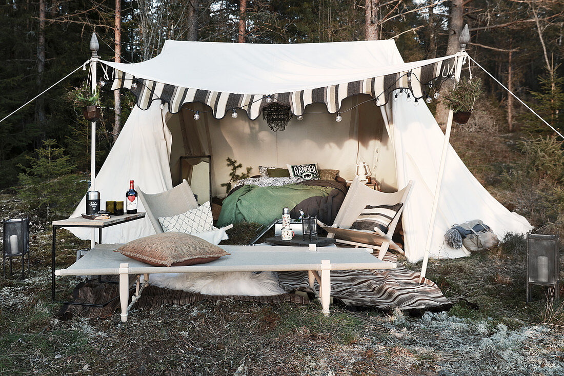 Feldbett und Stühle vor eingerichtetem Zelt mit Lichterkette Feldbett und Stühle vor eingerichtetem … – Bild kaufen – 12454501 ❘ living4media – Bild 1